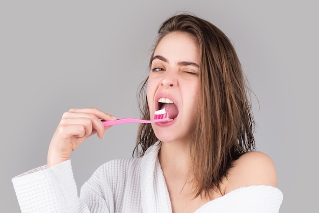 Grappig portret van een gelukkige mooie vrouw die haar tanden poetst met een tandenborstel geïsoleerde achtergrond