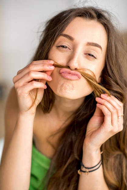 Grappig portret van een jonge vrouw die snor maakt van haar haar in de badkamer