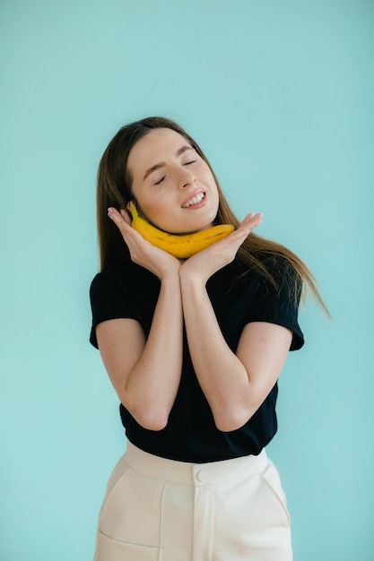 Grappig portret van jonge vrouw met banaan op kleurenachtergrond