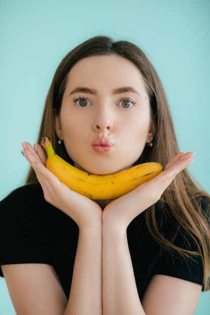 Grappig portret van jonge vrouw met banaan op kleurenachtergrond