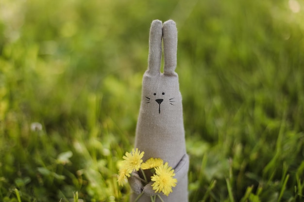 Grappig schattig handgemaakt speelgoedkonijn op gras op zonnige zomerdag