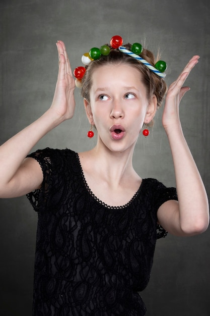Grappig tienermeisje met een krans van snoepjes op haar hoofd die voor de camera voor de gek houdt.