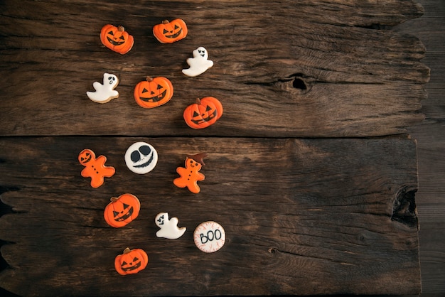 Grappige achtergrond voor Halloween van een mix van oranje en witte koekjes op een bruin houten tafel. Ruimte kopiëren