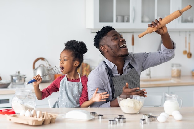 Grappige Afro-Amerikaanse familie die zingt tijdens het bakken thuis