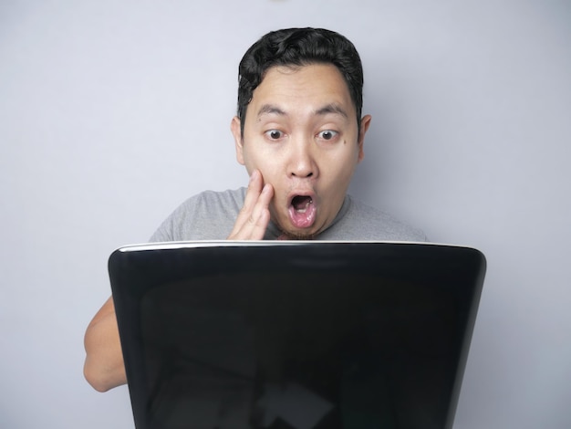 Grappige Aziatische man geschokt toen hij naar zijn laptop keek