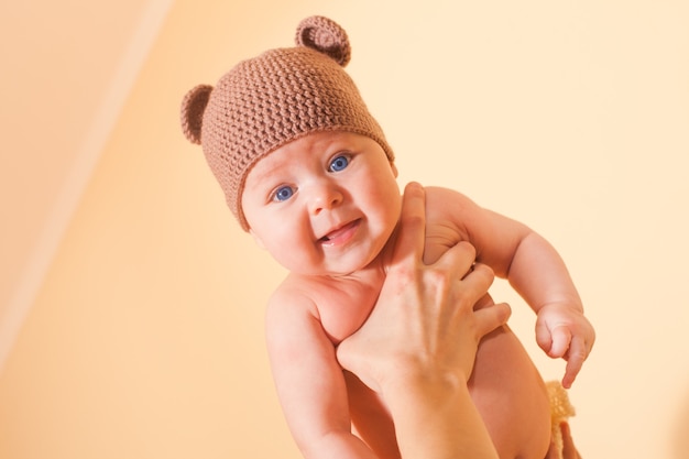 Grappige baby in berenhoed die op de hand van de moeder vliegt