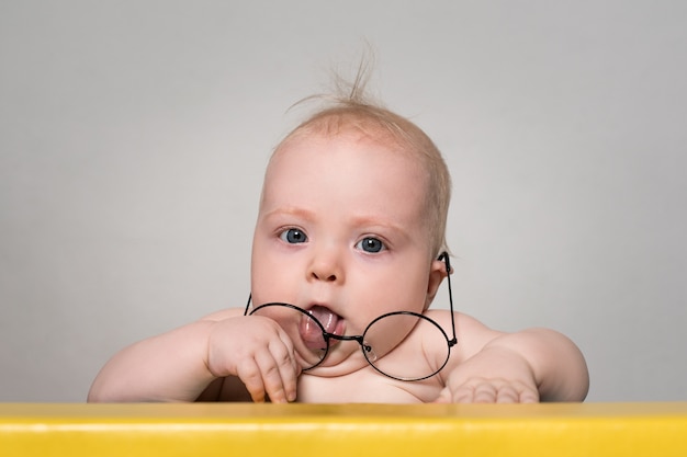 Grappige baby in grote ronde glazen aan de tafel.