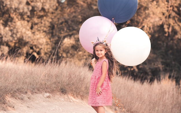 Grappige babymeisje met kleurrijke ballonnen in park