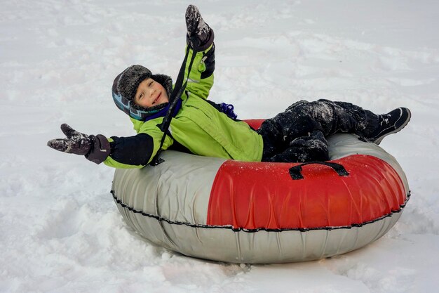 Grappige blanke jongen van 5 jaar oud rijdt in de winter op een grote opblaasbare cheesecake Winterpret en entertainment