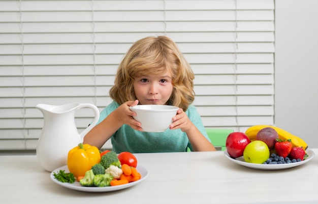 Grappige blonde kleine jongen ontbijt melk groenten en fruit gezonde voeding voeding voor kinderen