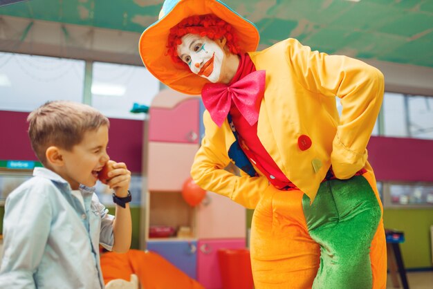 Grappige clown animator dansen met kleine jongens in de kleuterschool. Verjaardag vieren in de speelkamer, babyvakantie in de speeltuin.