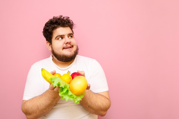 Grappige dikke man houdt bananen oranje groen mandarijn appel vast