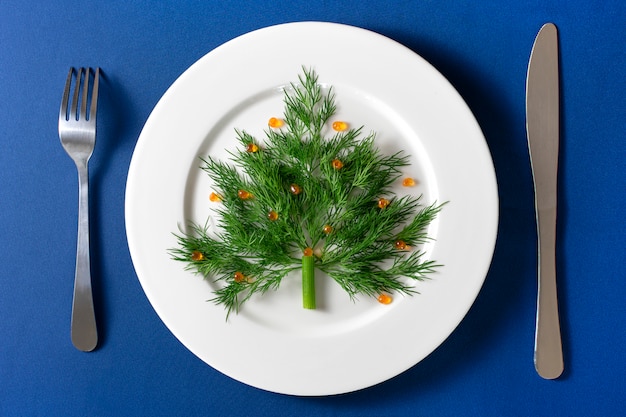 Grappige eetbare kerstboom gemaakt van dille en rode kaviaar. Serveeridee voor een feestelijk evenement.