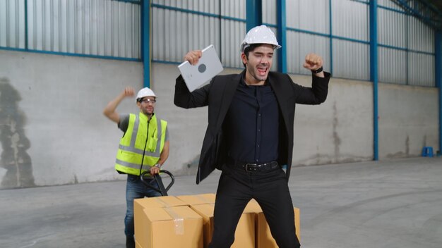 Grappige fabrieksarbeiders dansen in de fabriek. Gelukkige mensen aan het werk.