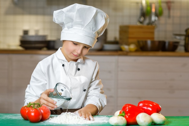 Grappige gelukkige jongen koken in de keuken van het restaurant