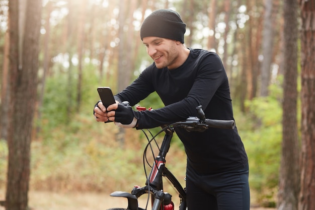 Grappige glimlachende sportman die zwarte sportkleren draagt