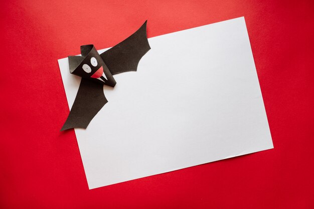 Grappige Halloween Bat gemaakt van papier op een rode achtergrond. Ansichtkaart op Helloween