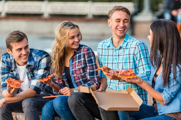 Grappige jonge studenten eten grote pizza&#39;s.