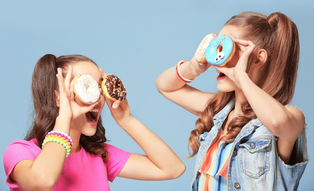 Grappige jonge vrouwen met lekkere donuts op blauw