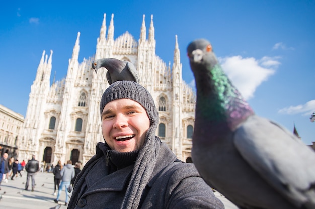 Grappige jongeman selfie met duiven te nemen in de buurt van de dom van milaan duomo