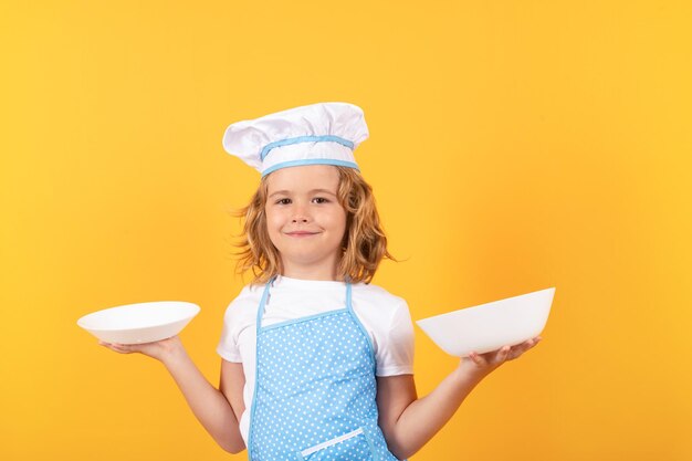 Grappige jongen chef-kok met keuken plaat studio portret Chef jongen jongen gezonde voeding maken Portret van klein kind in chef-kok hoed geïsoleerd op studio achtergrond Kind chef kookproces