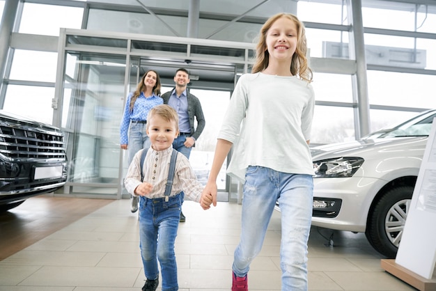 Grappige jongen met oudere zus invoeren in grote auto showroom