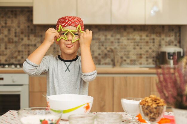 Grappige jongen plezier thuis, houdt koekjes vormen sterren voor h