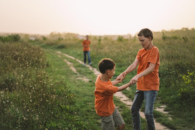 Grappige jongens broers in een oranje T-shirt buiten spelen op het veld bij zonsondergang Happy childrens lifestyle