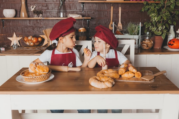 Grappige kinderen bereiden deeg, bakken koekjes in de keuken. Kleine koks in schorten houden paaskoekjes voor hun ogen.