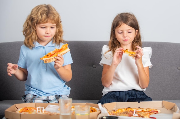 Grappige kinderen die pizza eten Klein meisje en jongen eten pizza