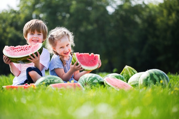 Grappige kinderen eten watermeloen buiten.