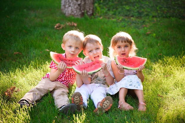 Grappige kinderen watermeloen buiten eten in de zomer park.