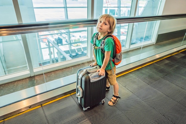 Grappige kleine jongen die op vakantie gaat met koffer op de luchthaven binnenshuis