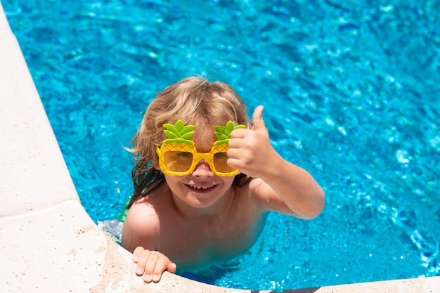 Grappige kleine jongen ontspannen in een zwembad met plezier tijdens de zomervakantie in een tropisch resort