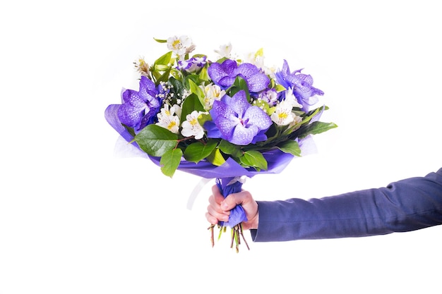 Grappige knappe jonge man met donker pak met een mooi boeket in de handen van witte en paarse bloemen geïsoleerd op een witte achtergrond