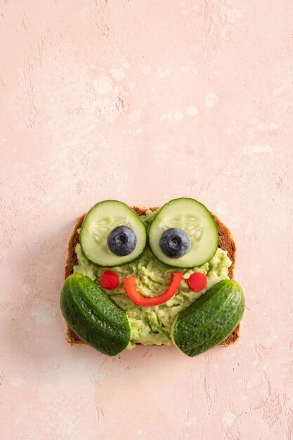 Foto grappige, leuke kikkertost met komkommer en avocado puree.