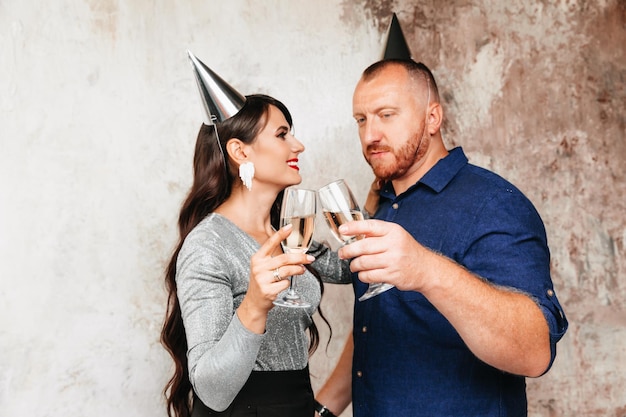 Grappige man en vrouw met hoeden op hun hoofd een feestelijk feest met champagne lifestyle-feest het paar viert een verjaardag of nieuwjaar