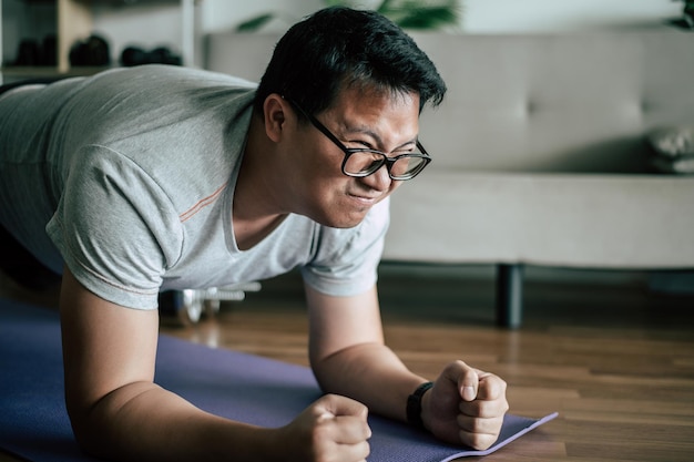 Grappige man met overgewicht met een bril probeert op de vloer te planken terwijl hij kopieerruimte voor de training doet