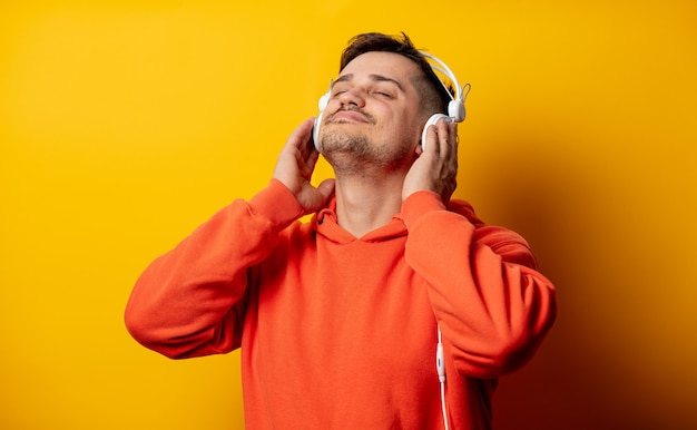 Grappige mens met hoofdtelefoons op gele muur