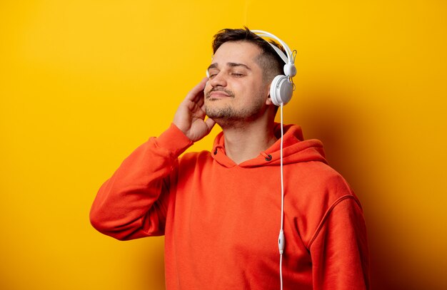 Grappige mens met hoofdtelefoons op gele muur