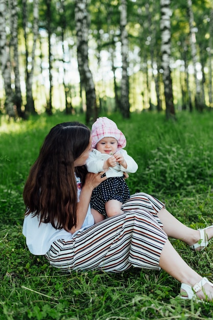 Grappige moeder met baby zittend op het gras