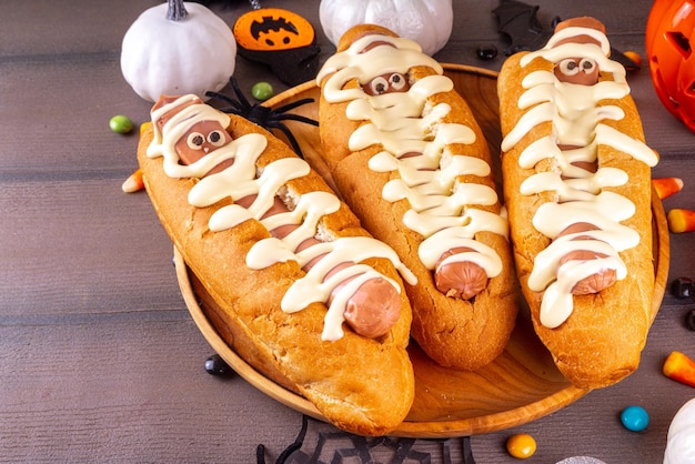 Grappige mummie-hotdogs voor Halloween-feest of kindervakantiebrunch Klassieke hotdogs met kaasogen en kaasachtige mayonaise met Halloween-decor bovenaanzicht kopieerruimte