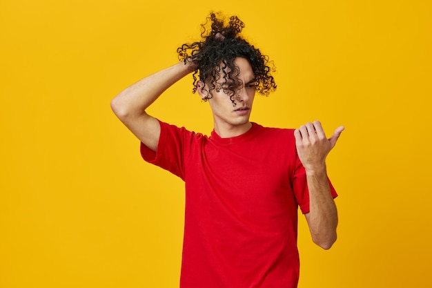 Grappige peinzende blanke jonge man in rode tshirt wijsvinger op vrije plaats poseren geïsoleerd op gele studio achtergrond Het beste aanbod met gratis plaats voor reclame Emoties voor alledaags concept