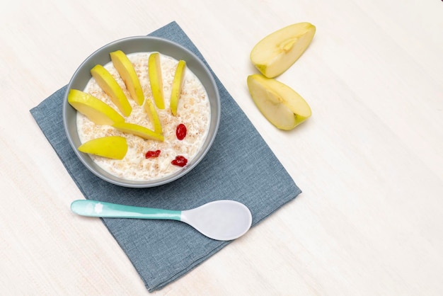 Grappige schattige kinderen kinder babys ontbijt lunch havermoutpap in kom eruit egel decoratie met appel gedroogde kersen bessen fruit voedsel kunst op witte houten tafel