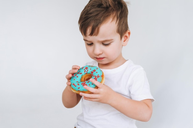 Grappige schattige peuter jongen met donut op de witte achtergrond