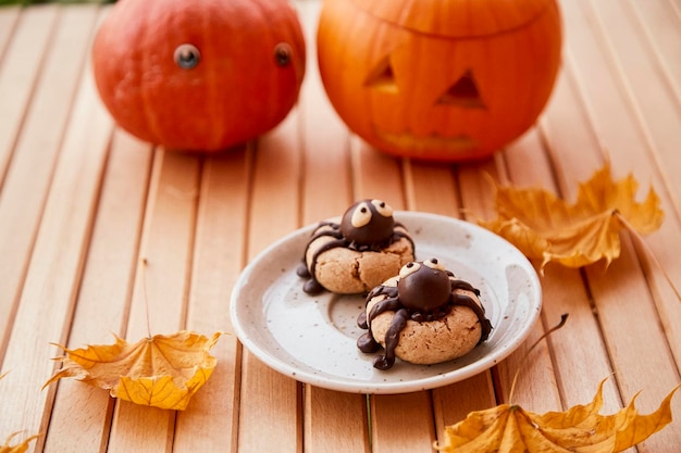 Grappige spinnenkoekjes met Halloween-pompoen tussen herfstbladeren