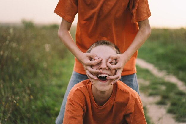 Grappige tweelingbroer jongens in oranje t-shirt buiten spelen op veld bij zonsondergang Happy children lifestyle