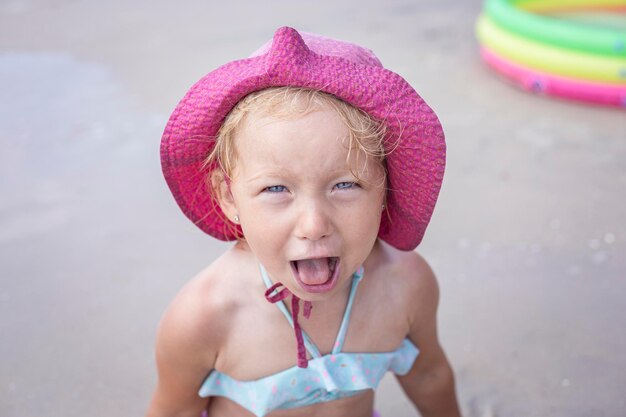 Grappige vrolijke kleine jongen in een panama hoed op het strand.