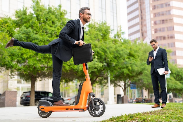 Grappige zakenman in een pak rijden op een elektrische scooter op zakelijke bijeenkomst gekke zakenman rijden