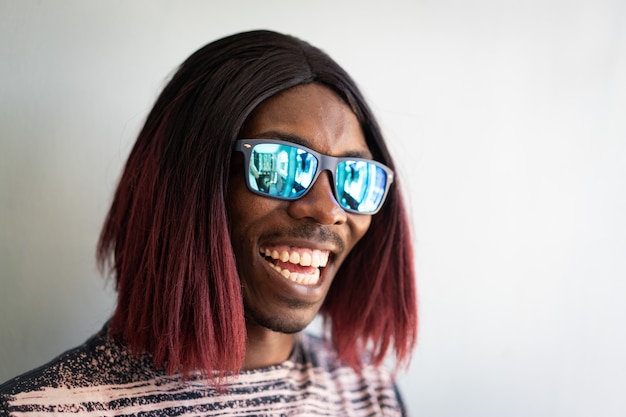 Grappige zwarte jongen met lang haar en zonnebril lachen